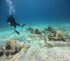 Scuba diver exploring the underwater sculptures at MUSA (Subaquatic Museum of Art) in the crystal clear waters of Cancun, Mexico.