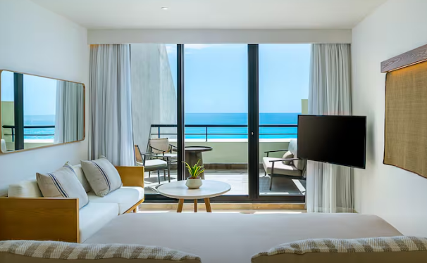 Suite remodelada en Paradisus Cancún con balcón privado, vista panorámica al mar Caribe y sala de estar moderna.