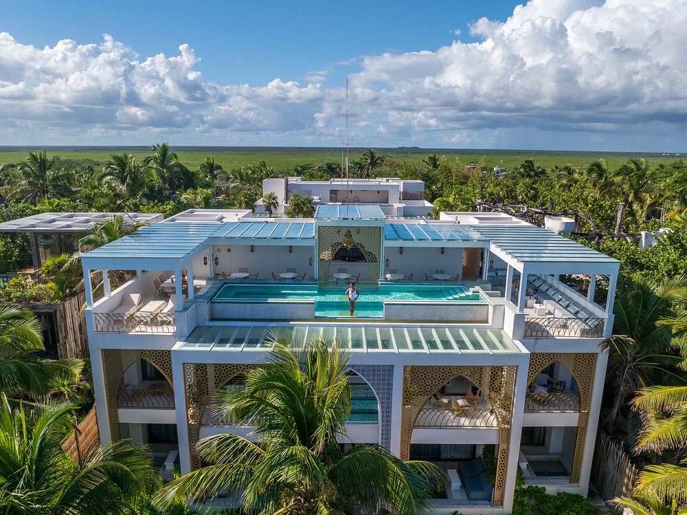 Fachada moderna del hotel Sana Tulum con piscina infinity en el rooftop, detalles arquitectónicos geométricos y vistas a la selva tropical.