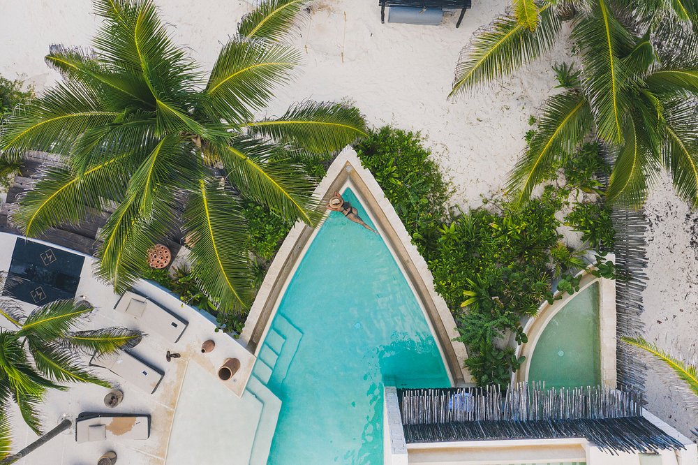 Vista aérea de una suite de lujo en Hotel Ma'xanab Tulum con piscina privada frente al mar, rodeada de palmeras y arena blanca.