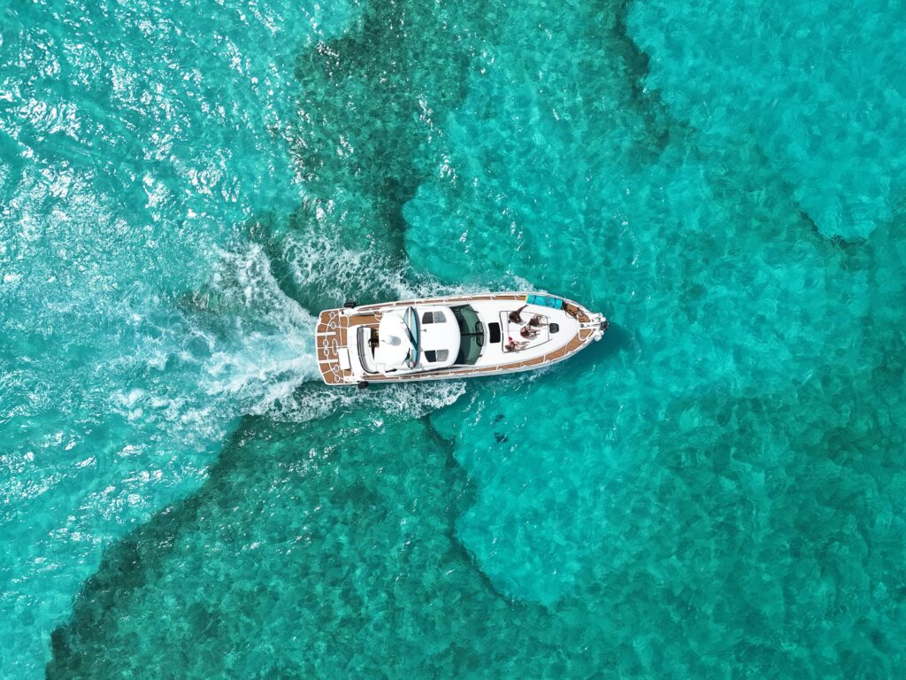 Vista aérea de un yate de lujo navegando por las aguas turquesas cristalinas de Cancún, ideal para tours privados y eventos exclusivos en el Caribe.